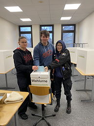 Das Foto zeigt drei Schülerinnen und Schüler bei der Stimmabgabe (Februar 2025)