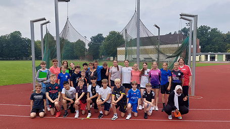Das Foto zeigt die Schülerinnen und Schüler der 7ems auf dem Sportplatz zusammen mit ihren zwei Lehrerinnen.